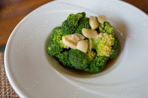 Stir fried broccoli with garlic in oyster sauce inside beautiful white round plate.