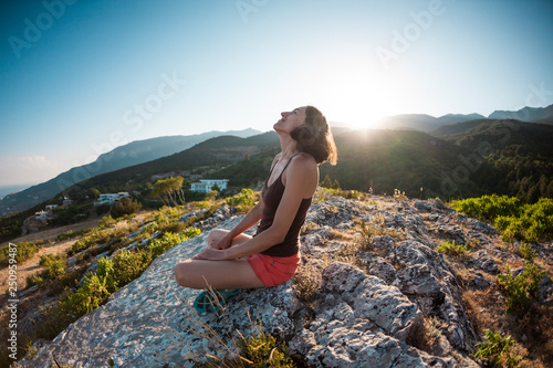 A girl is sitting on top of a mountain and smiling.