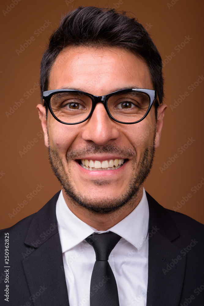 Young handsome Hispanic businessman against brown background Young handsome Hispanic businessman against brown background