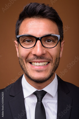 Young handsome Hispanic businessman against brown background