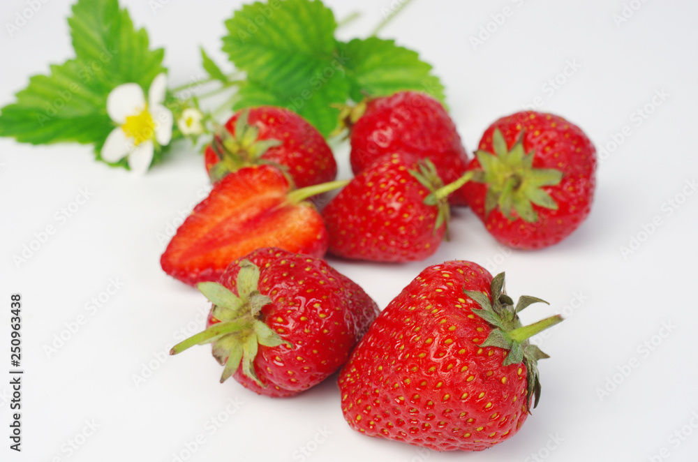 Ripe strawberries with leaves and flowers on white, close-up Ripe strawberries with leaves and flowers on white, close-up