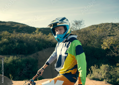 Young man sitting on mountain bike in green valley  photo