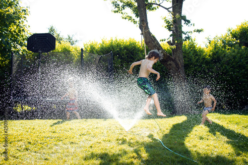Boys playing in sprinkler 