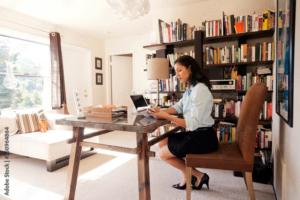 Woman sitting at desk writing in notepad Woman sitting at desk writing in notepad