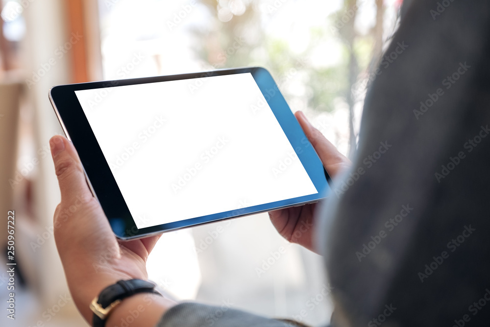 Mockup image of a woman holding black tablet pc with blank white screen while sitting in cafe - obrazy, fototapety, plakaty 