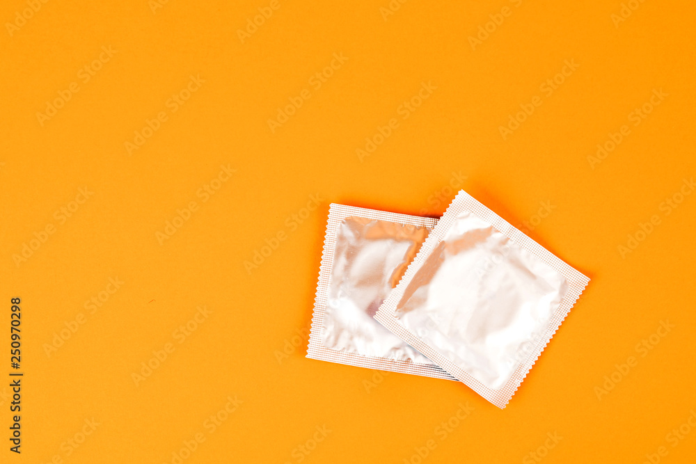 Condoms on an orange background. The concept of prevention and safe sex. Condoms on an orange background. The concept of prevention and safe sex.