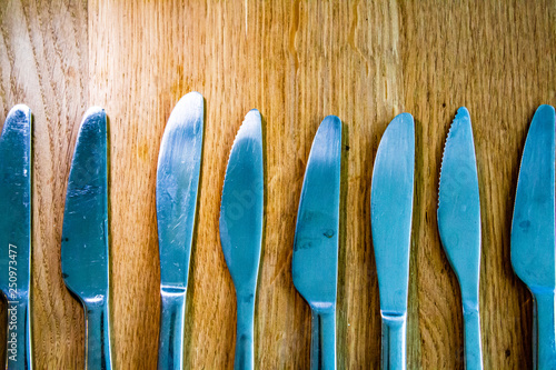 Many Knives in a line on a wooden table