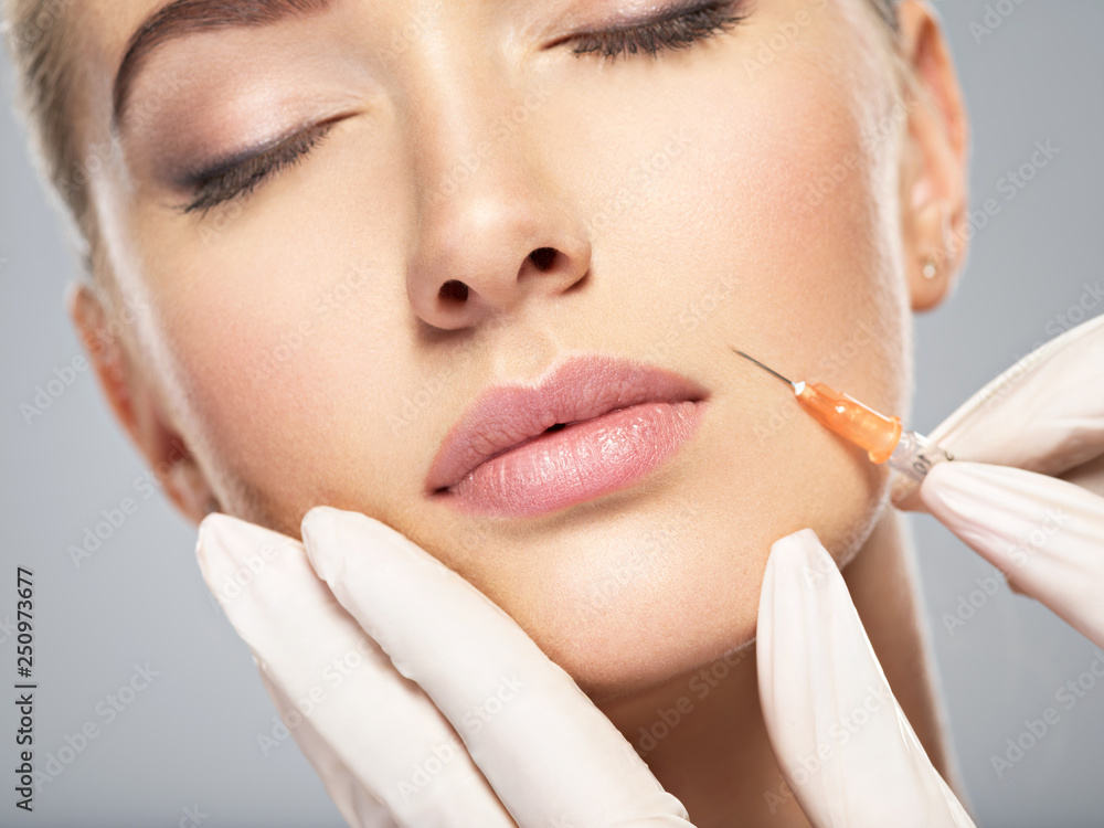 Woman getting cosmetic injection of botox in cheek Woman getting cosmetic injection of botox in cheek