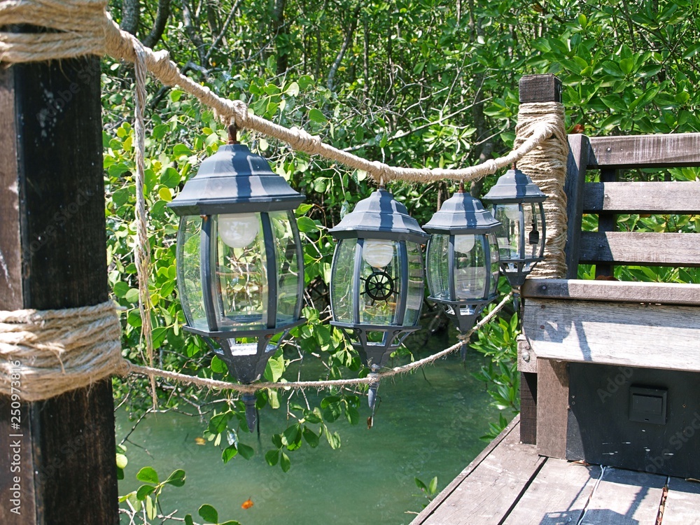Bridge in garden and rope railings with decorative lanterns. Thailand's  mangroves and a nautical-style bridge for walking along them. Sea stylish  outdoors decor with a foliage on a background. Stock Photo