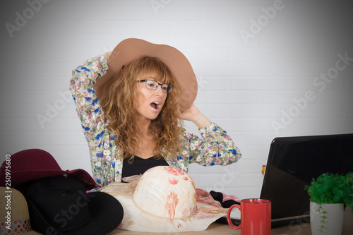 girl trying hats and fashion in front of the computer on the Internet photo