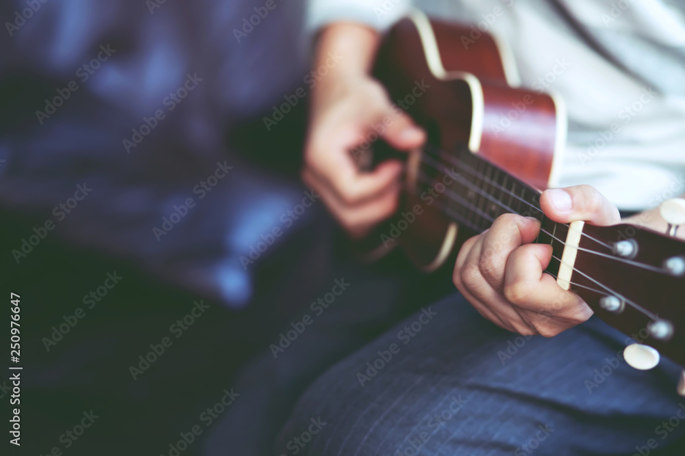 Closeup of young man hands playing acoustic guitar ukulele at the sofa sit Enjoy living room. Closeup of young man hands playing acoustic guitar ukulele at the sofa sit Enjoy living room.