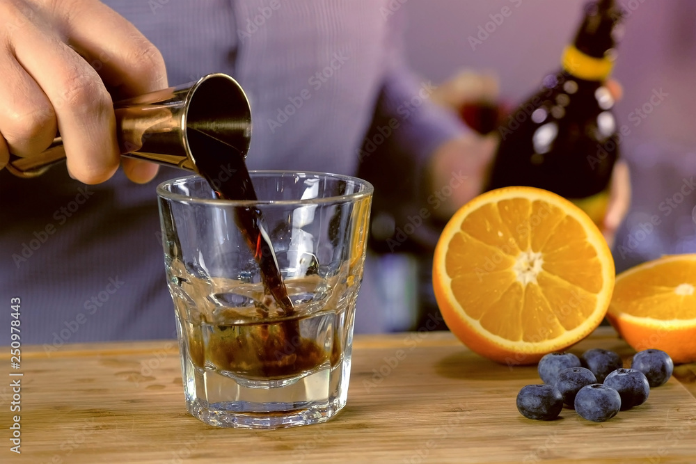 Barman pours kahlua from jigger to rocks glass with tequila preparing alcohol cocktail. Hands close-up. Barman pours kahlua from jigger to rocks glass with tequila preparing alcohol cocktail. Hands close-up.