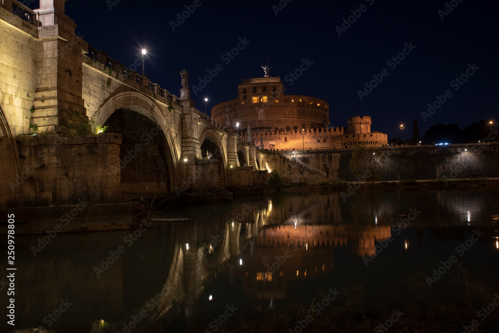 beautiful view of Castel Sant'Angelo and the bridge at night with reflections on the Tiber river. Rome Italy