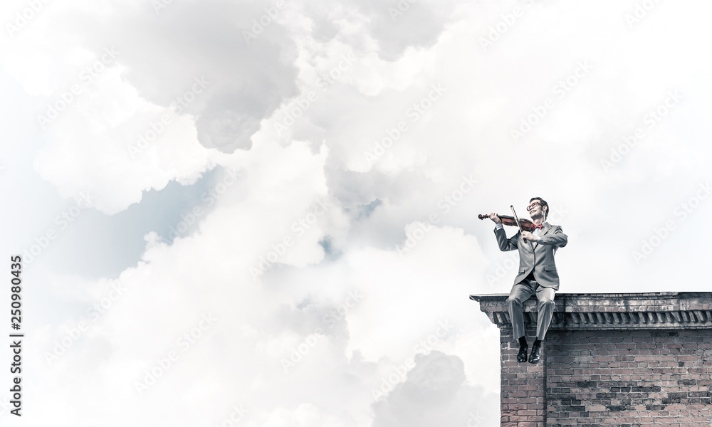 Handsome violinist in glasses on building edge play his melody Handsome violinist in glasses on building edge play his melody
