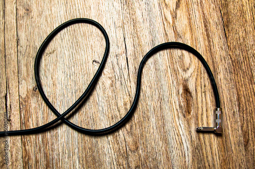 Black long Guitar lead on wooden floor 