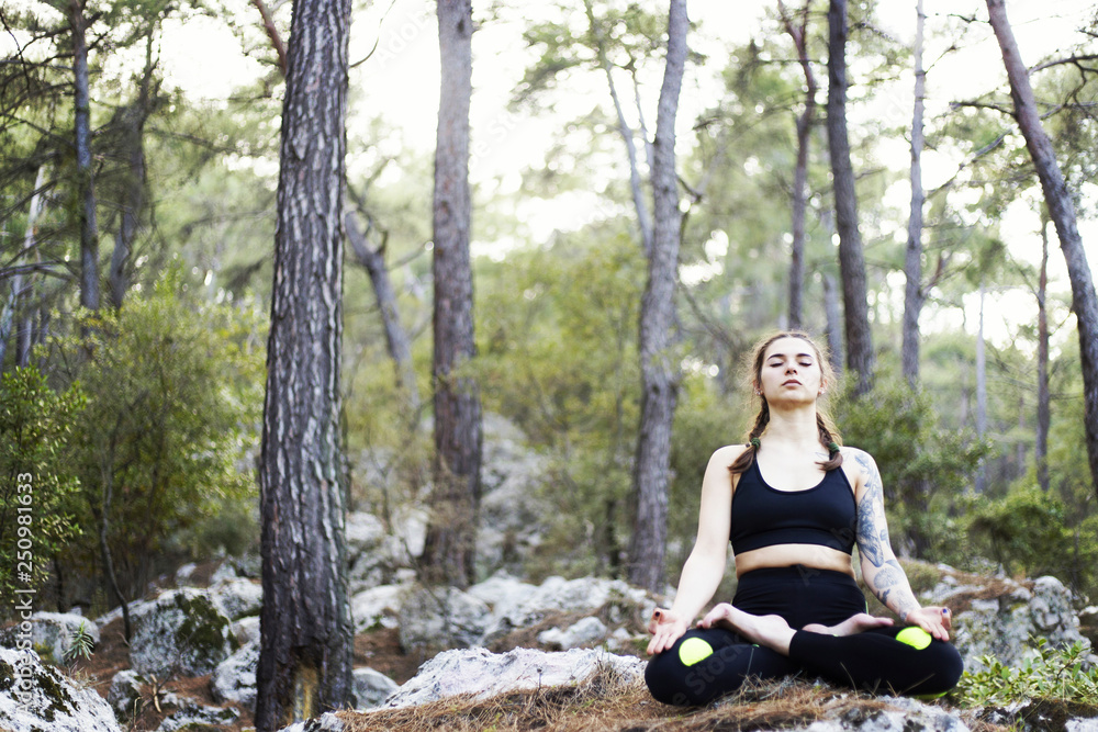woman meditating in lotus posture, doing yoga on top of the mountain on a rock in nature in the forest woman meditating in lotus posture, doing yoga on top of the mountain on a rock in nature in the forest