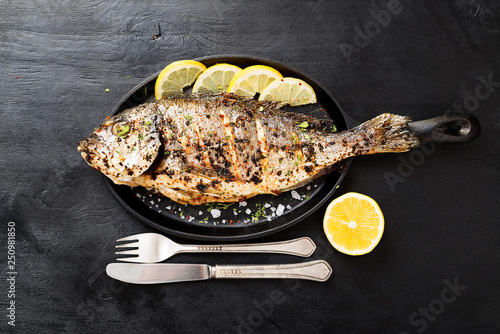 Tasty grilled fish dorado with  lemon on kitchen table.