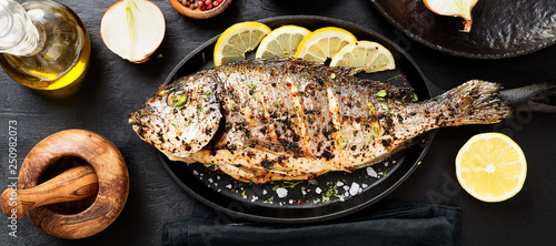 Photo Tasty grilled fish dorado with  lemon on kitchen table.