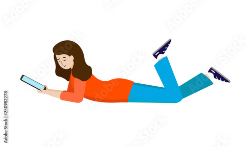 The girl lies on her stomach and holds a tablet, an e-book. Young woman resting, reading a book.