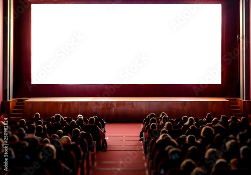 People in the cinema auditorium with empty white screen. photo