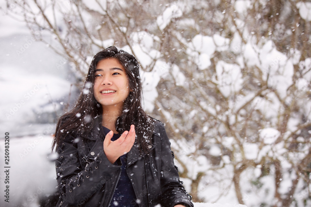 Teen girl outdoors during snowfall wearing black leather jacket Teen girl outdoors during snowfall wearing black leather jacket