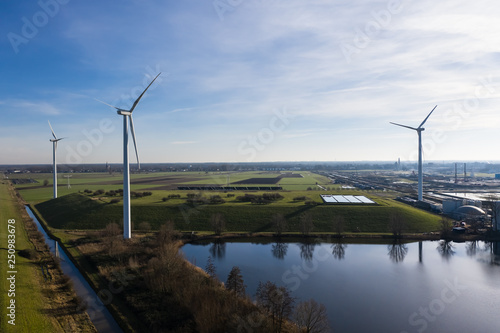 Wind turbines generating eco friendly green energy for a better environment on fields next to a canal near Waalwijk, Noord-Brabant, Netherlands. photo
