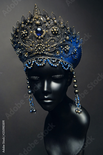 Head of woman mannequin in blue decorated Russian kokoshnick, grey studio background