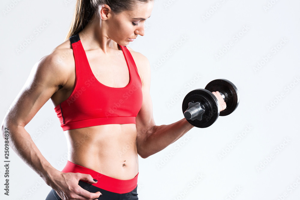 Fit woman with dumbbells in sportswear red-black close-up. on a gray background. Fit woman with dumbbells in sportswear red-black close-up. on a gray background.