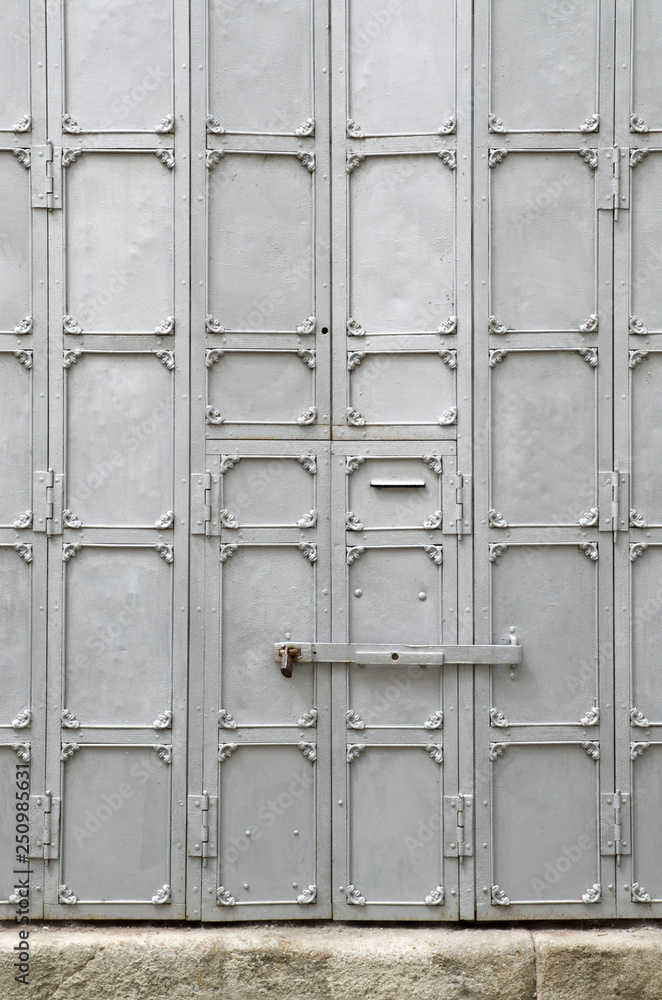 Old small metal door with a padlock, part of a large door Old small metal door with a padlock, part of a large door