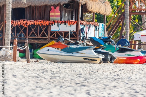 Row of Jet Skis to hire on a beautiful white Caribbean sandy beach on the Riviera Maya, Mexico beside a surf shack