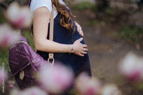 pregnant woman in magnolia flowers in a botanical garden