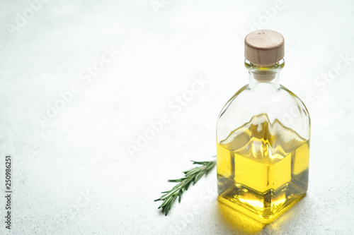 Fresh rosemary herb with oil and spices on a light background.