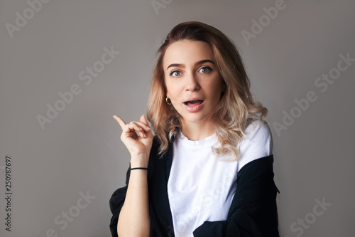 Wallpaper Mural Young pretty girl holding finger up having idea and posing. Close-up portrait of amazed pretty young woman pointing with finger, looking at camera with open mouth Torontodigital.ca