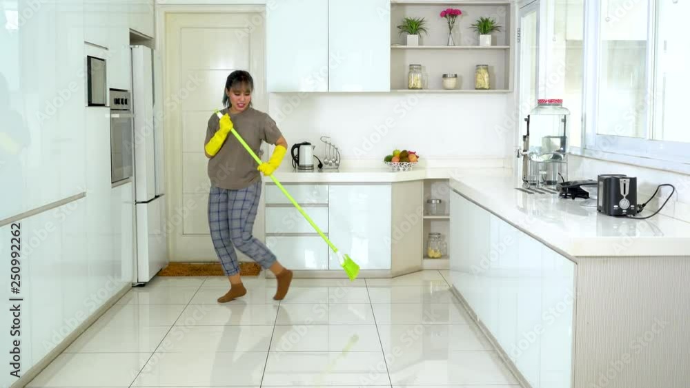 Beautiful young woman dancing in the kitchen while sweeping the floor at home. Shot in 4k resolution Beautiful young woman dancing in the kitchen while sweeping the floor at home. Shot in 4k resolution
