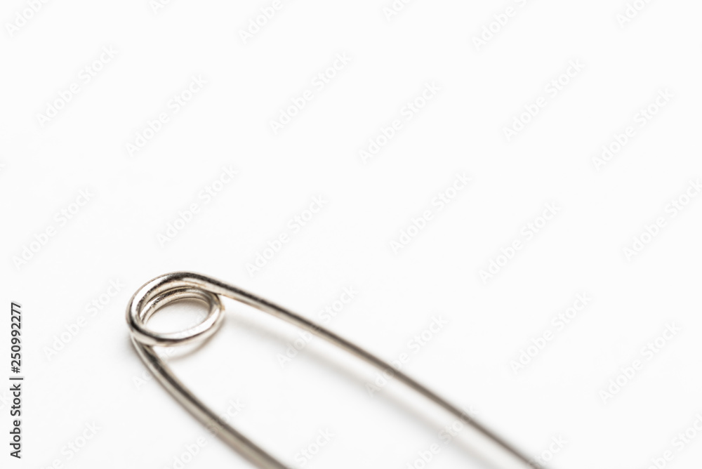 A close-up or macro shot of the spring coil of a common safety pin set on a white background. A close-up or macro shot of the spring coil of a common safety pin set on a white background.