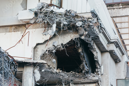 Photo of destroyed building, protruding reinforcement/ demolition of a building, house ruins, reconstruction, bricks and metal/ hole in the corner of the building, abandoned hotel,multi-storey bldng.