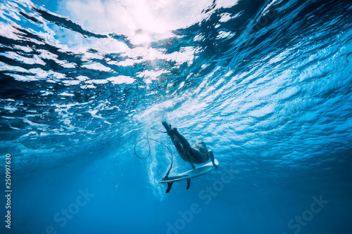 Attractive surfer woman dive underwater with under wave in blue ocean.