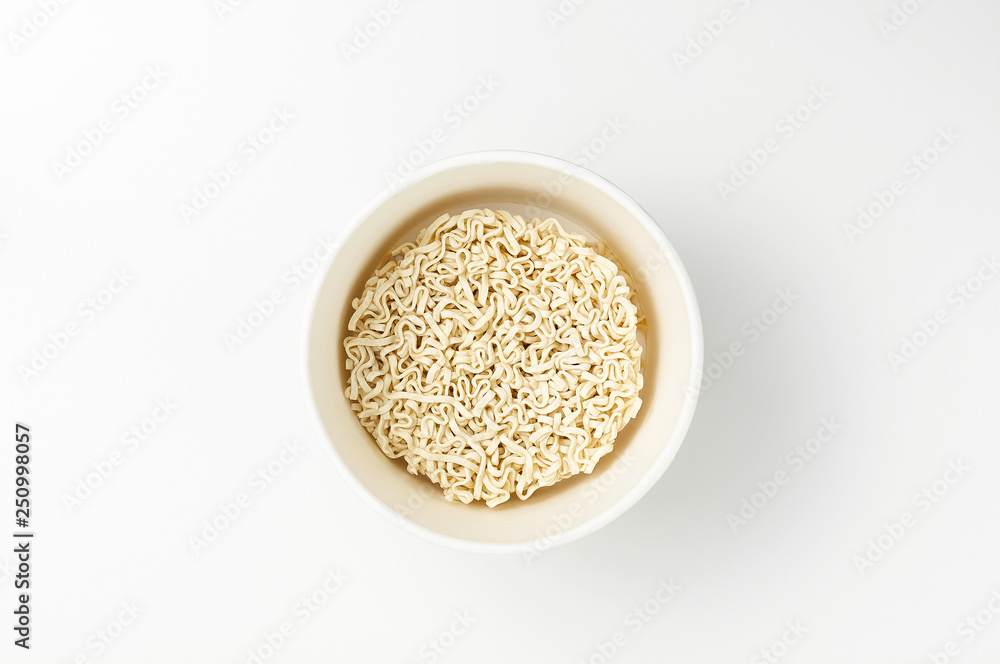 Overhead view of bowl with raw instant Asian egg noodles on white background