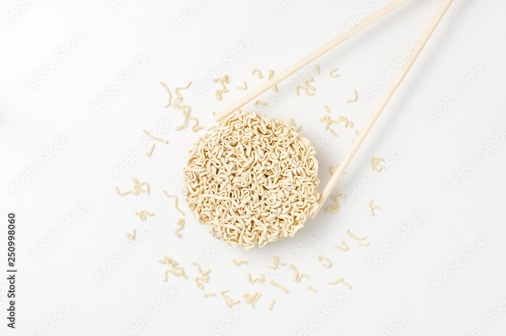 Overhead view of raw instant Asian egg noodles shaped in the form of a circle and chopsticks