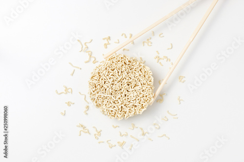 Obraz na płótnie Overhead view of raw instant Asian egg noodles shaped in the form of a circle and chopsticks w salonie