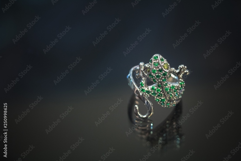 Gecko shaped ring with emeralds on a dark background Gecko shaped ring with emeralds on a dark background