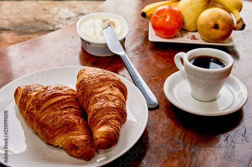 Coffee and croissant breakfast on a vintage wooden table. Espresso  croissants  cream cheese and fruits. 