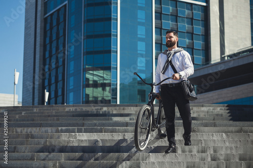 Bearded businessman carrying his bicycle on stairs