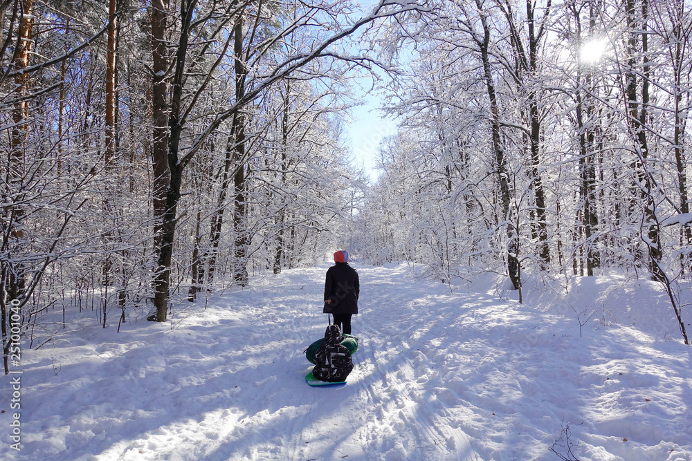 Mom rolls her little son on tubing in the Park in the winter. Happy family outdoors. winter fun for young children.