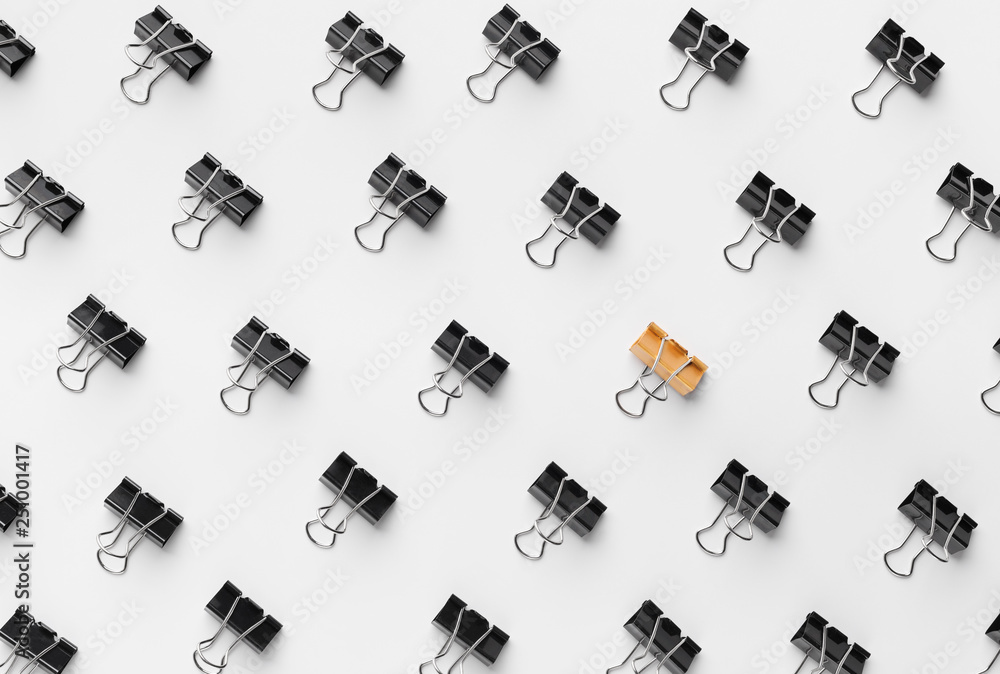 Golden binder clip standing between black ones Golden binder clip standing between black ones