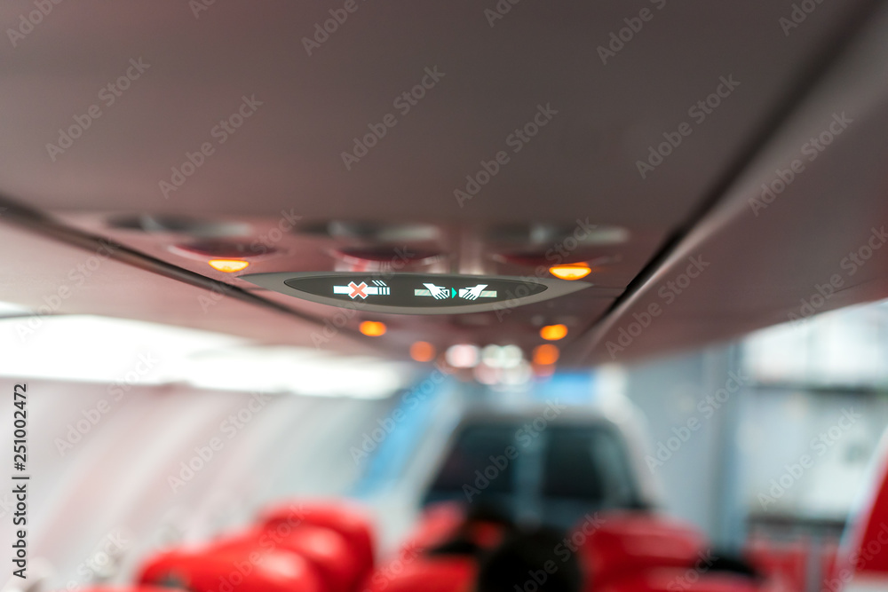 closeup airplane Console panel; lamp, light, need help button, air condition, sefty belt and no smoking lighting sign.