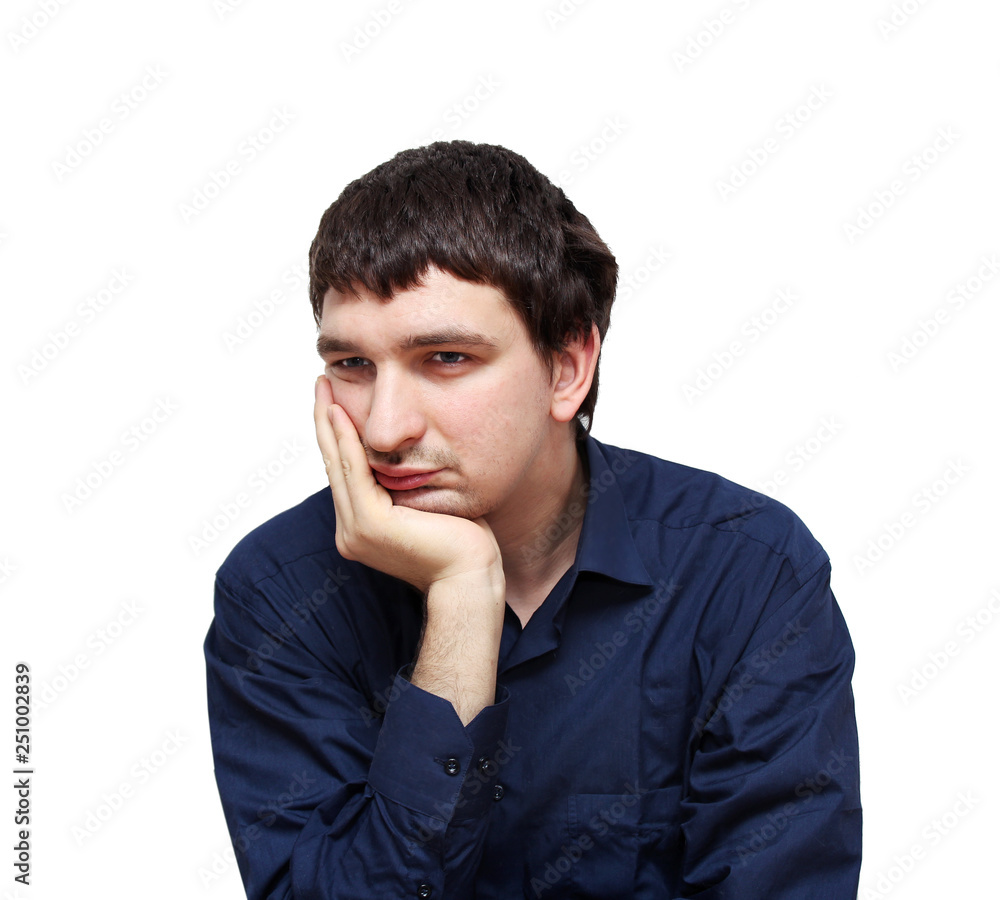 Sad young man in dark blue shirt sitting and propping his head by hand. Isolated on white. Sad young man in dark blue shirt sitting and propping his head by hand. Isolated on white.
