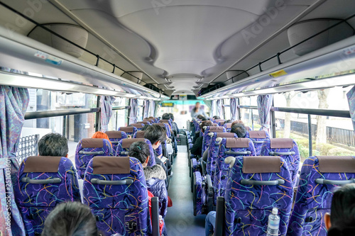 Fotografi People on the bus were sitting listen to tour guide who standing at front of row