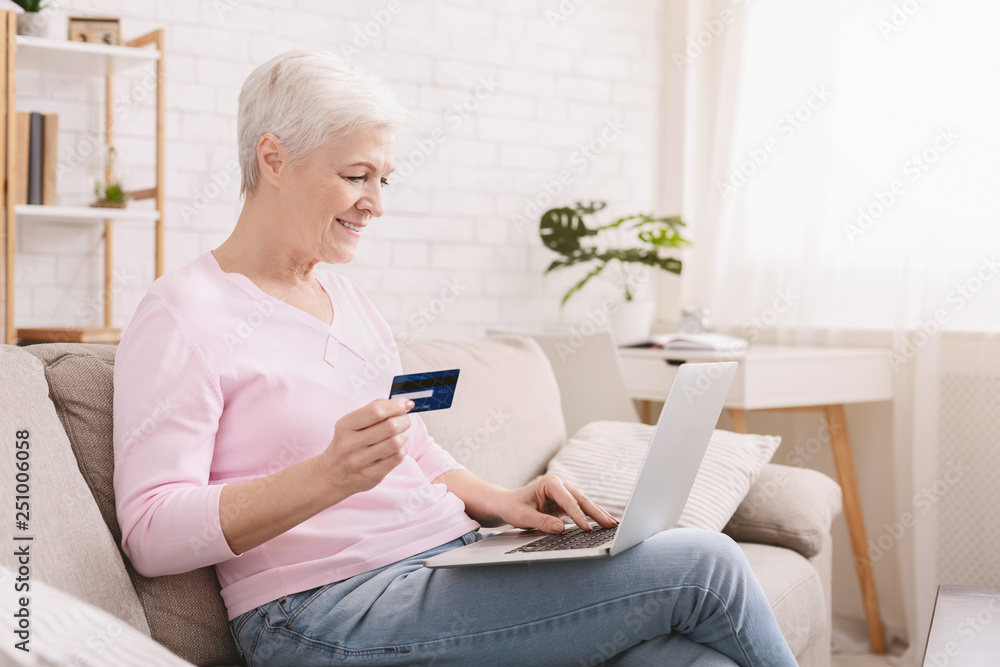 Mature woman shopping online with credit card and laptop Mature woman shopping online with credit card and laptop