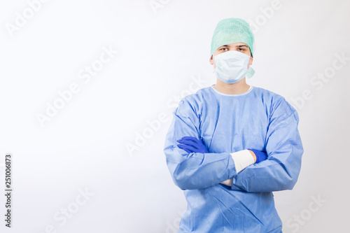 Surgeon doctor in sterile gloves preparing for operation in hospital. He is wearing surgical cap and blue gown photo